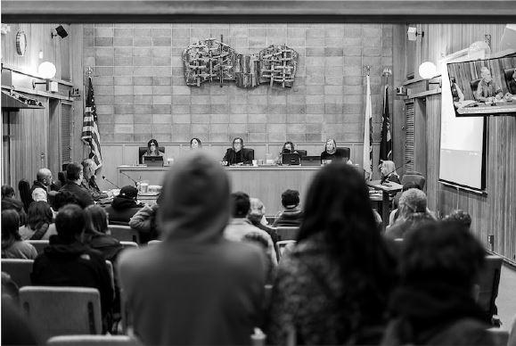 black and white photograph showing Arcata City Hall and people standing to speak